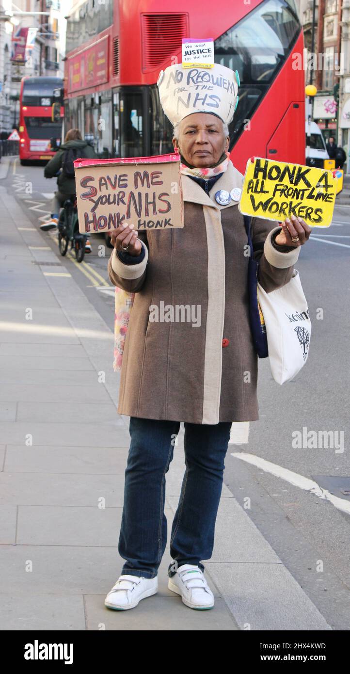 Protestor femenino de pie con signos- Salvemos el NHS fuera de los Tribunales Reales de Justicia, Londres, Reino Unido Foto de stock
