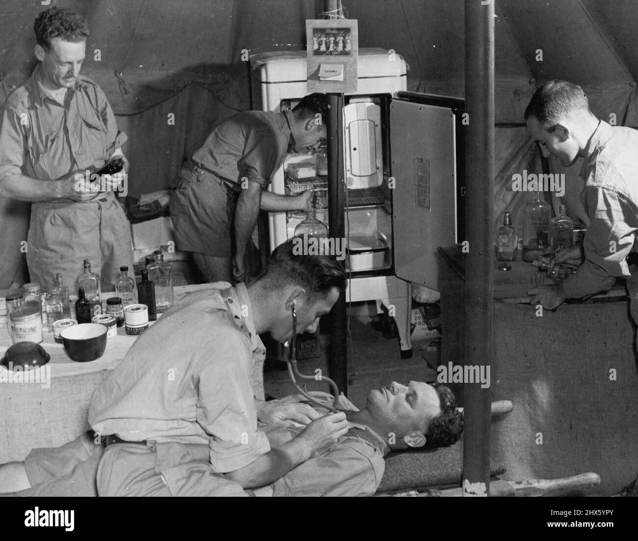 El A.A. M.C. es conocido por su espléndido equipo y su personal. Capitán N.R. Godby haciendo un diagnóstico en uno de los hospitales de campo. 26 de julio de 1940. (Foto del Departamento de Información de la Commonwealth).; The A.A. M.C. es conocido por su espléndido equipo y su personal. Capitán N.R. Godby haciendo un diagnóstico en uno de los hospitales de campo. Foto de stock