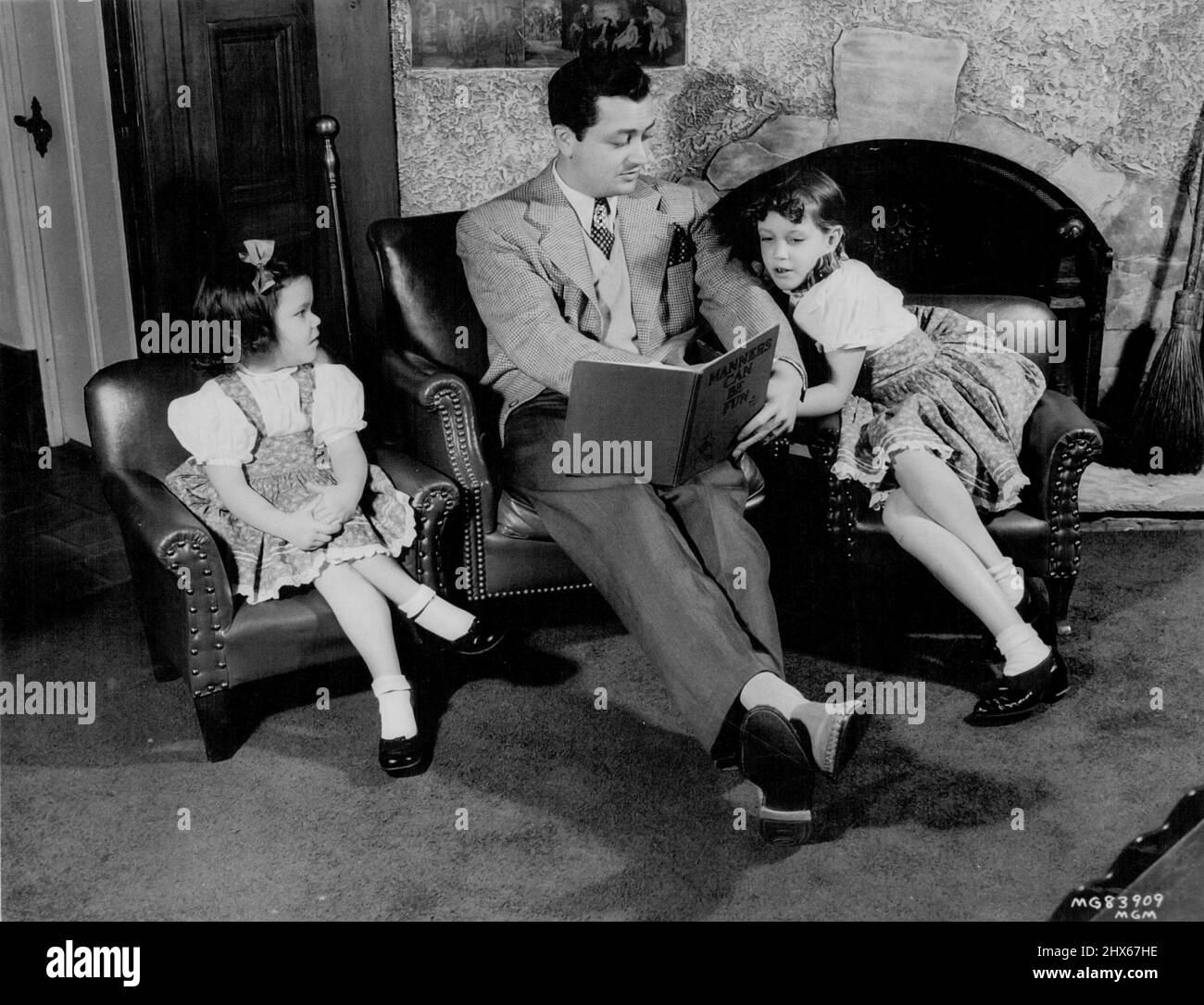 Robert Young, actor de Metro-Goldwyn-Mayer, pasa sus días fuera del trabajo de estudio leyendo y retozando con sus dos hijas, Carole Ann y Barbara Queen. La película más nueva de los actores para ***** . 29 de octubre de 1947. Foto de stock