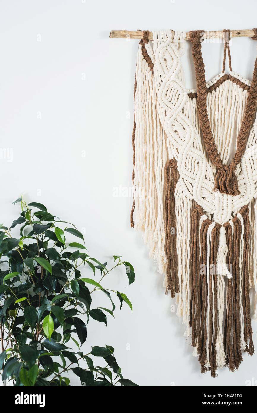 Panel de pared en el estilo de boho hecho de hilos de algodón en color natural utilizando la técnica macrame para la decoración del hogar. Primer plano Foto de stock