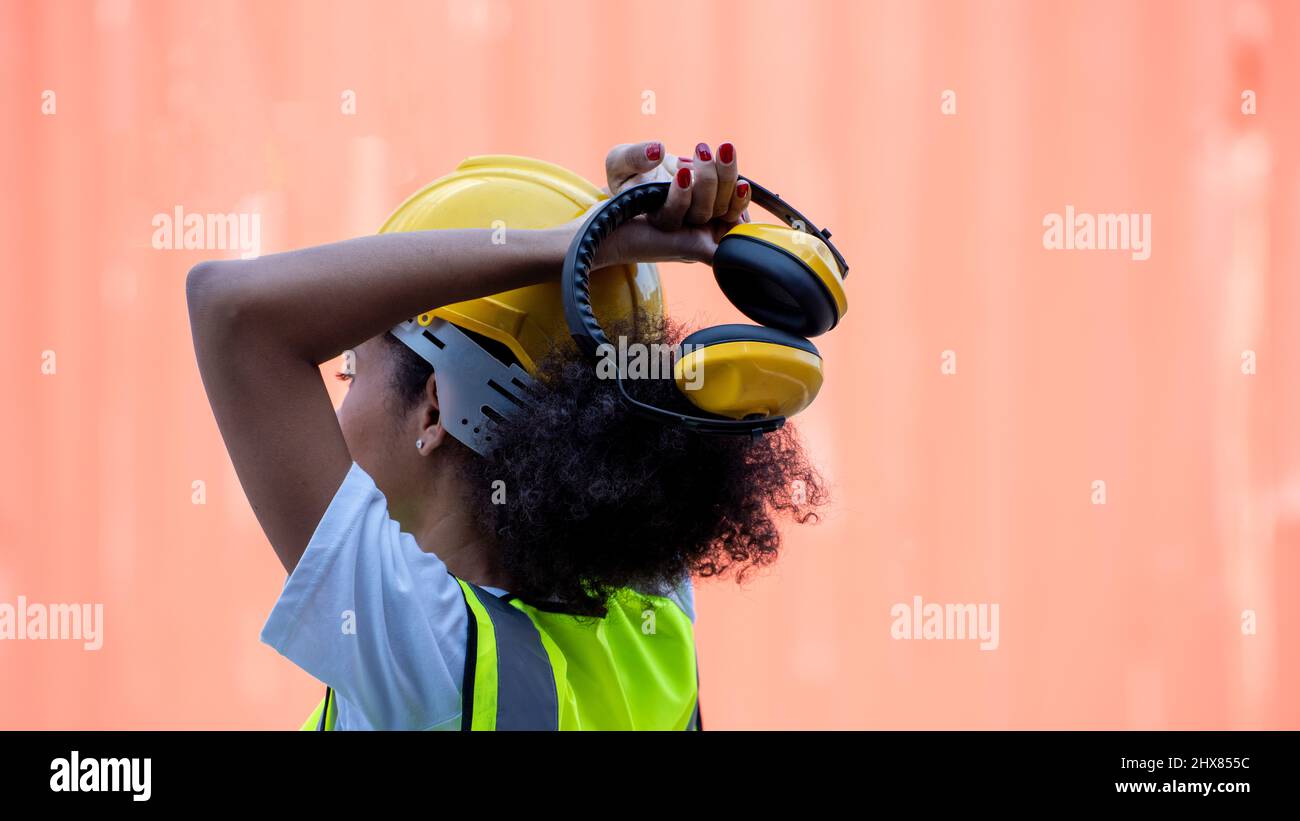 Mujer trabajadora inspector que sostiene y prepara la cancelación de ruido sobre la cabeza Foto de stock