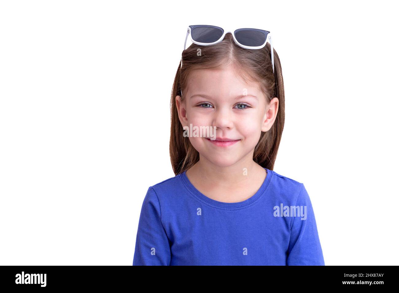 Niño sonriente usando gafas de sol blancas en la cabeza, aisladas sobre  fondo blanco mirando la cintura de la cámara para arriba niña caucásica de 5  años en azul Fotografía de stock -