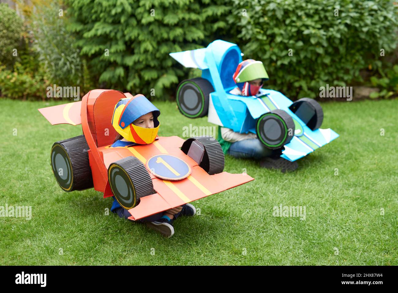 Niños con cardboard modelos de coches de carreras/disfraces, jugando en el  jardín Fotografía de stock - Alamy