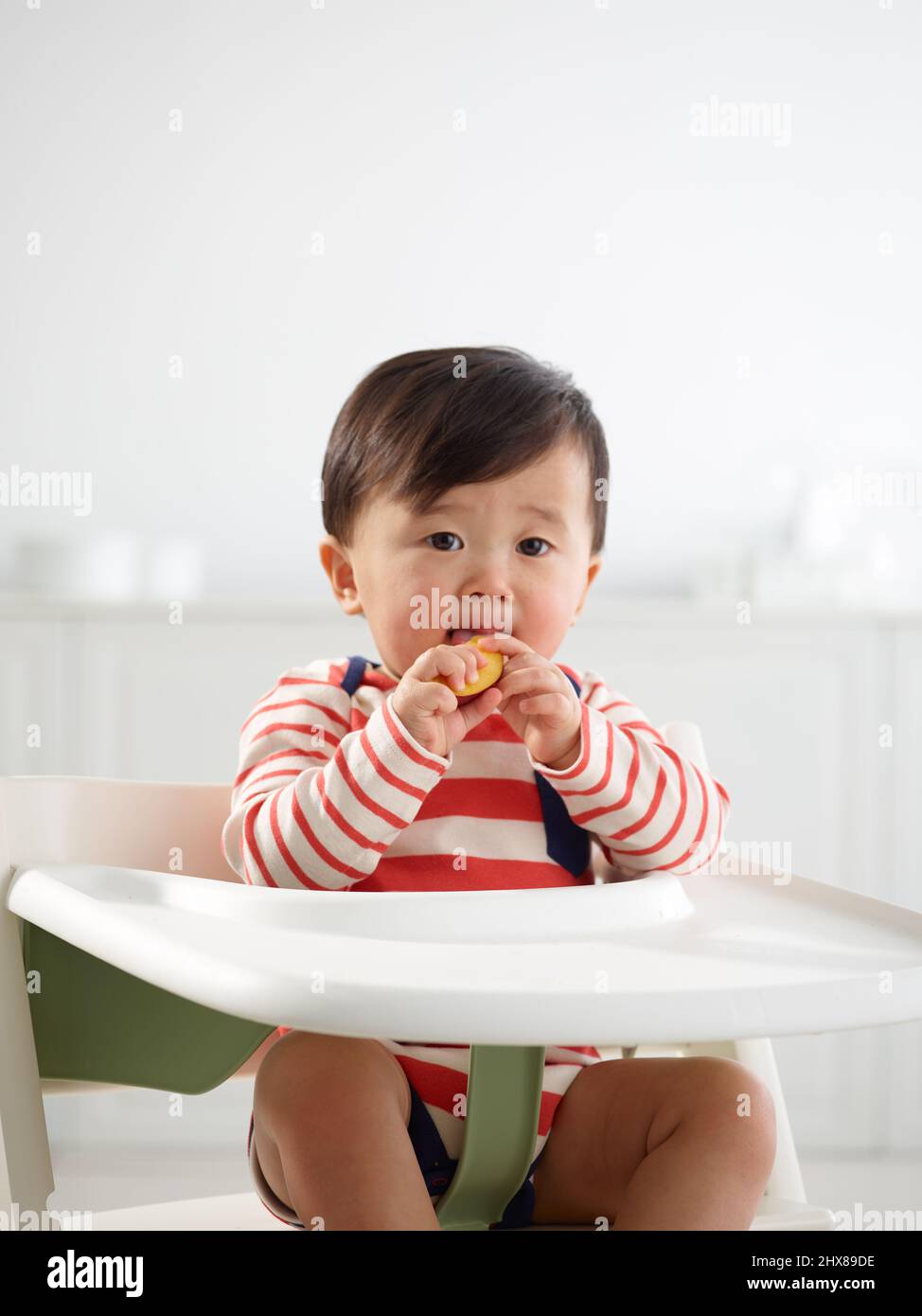 Bebé de 11 meses comiendo en trona Foto de stock