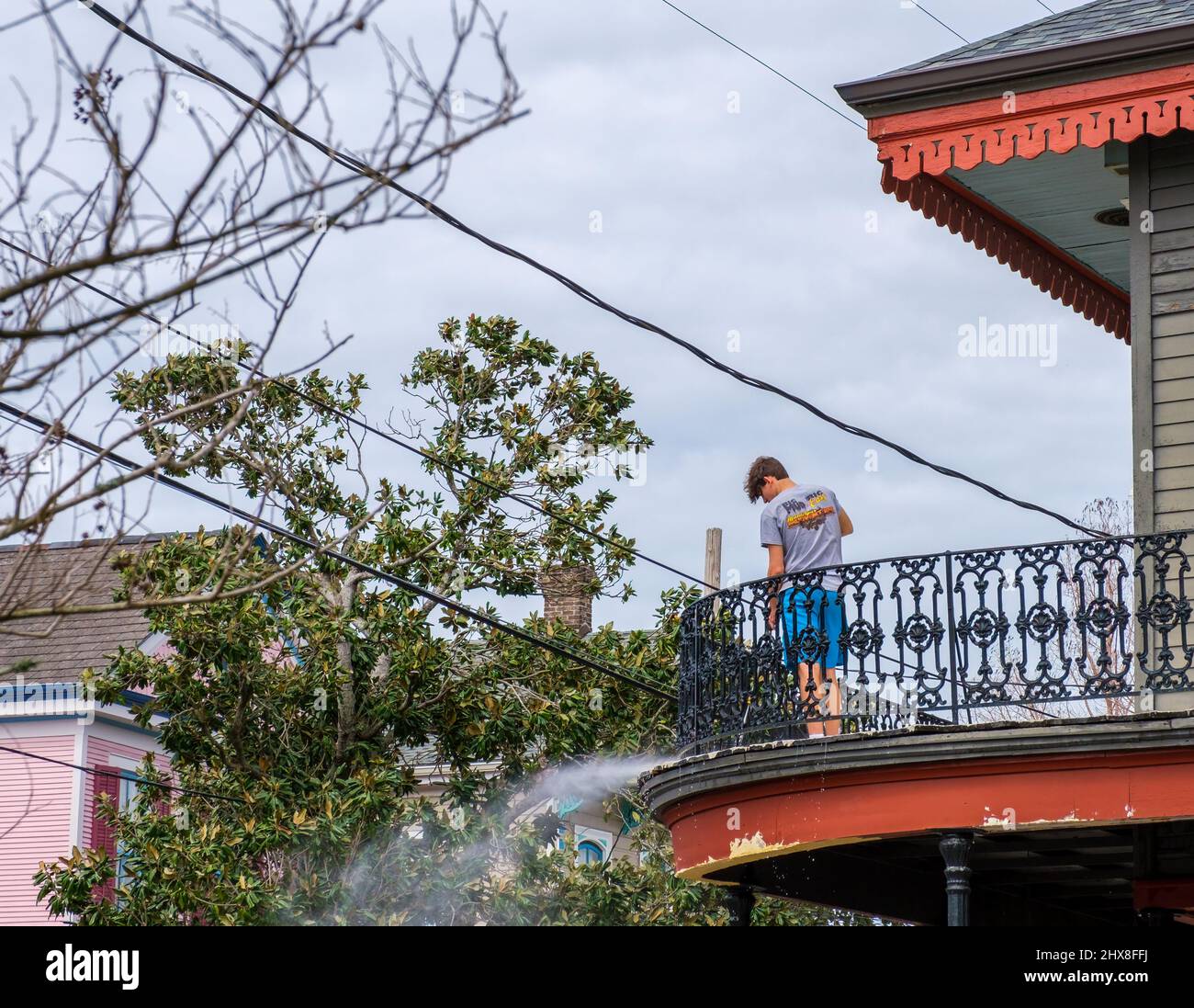 NUEVA ORLEANS, LA, EE.UU. - 5 DE MARZO de 2022: Hombre joven a presión lavando su balcón en su casa histórica en Argel Point Foto de stock