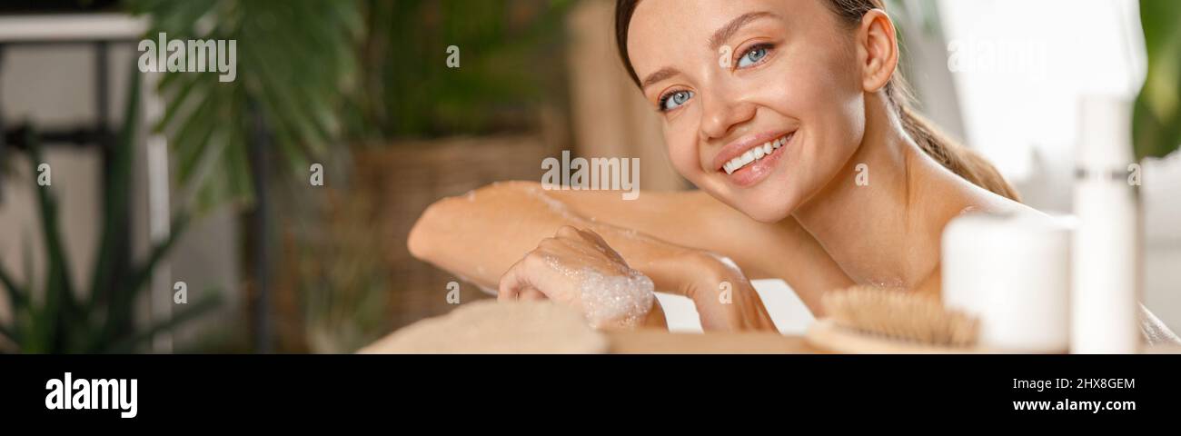 Retrato de una encantadora mujer joven sonriendo con la cámara mientras cuidaba su cuerpo en un spa tropical Foto de stock