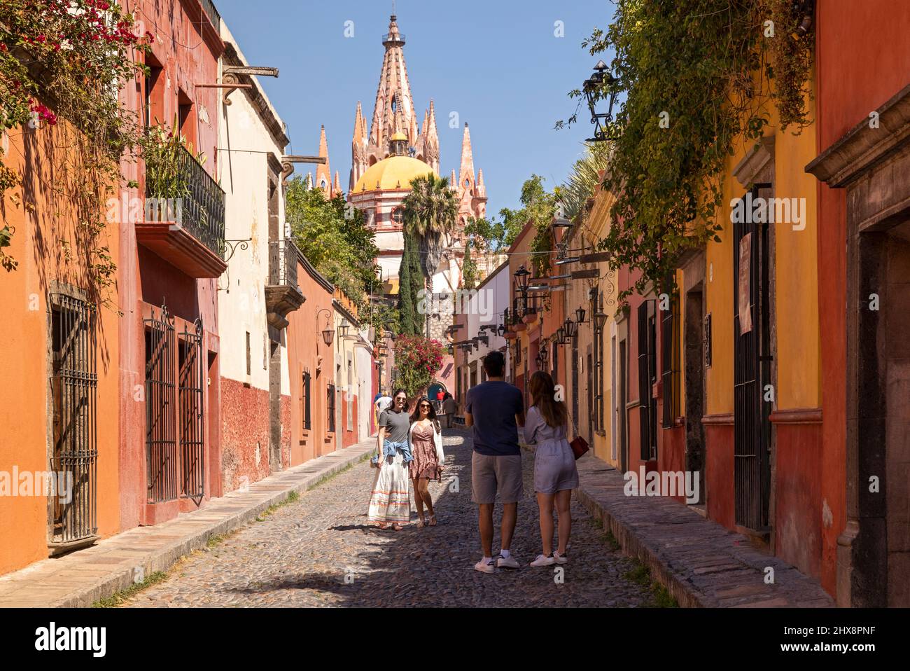 México, Guanajuato, San Miguel de Allende, una calle en la ciudad con casa típica y tiendas que conducen a la ciudad con la Parroquia de San Miguel Arcángel Foto de stock