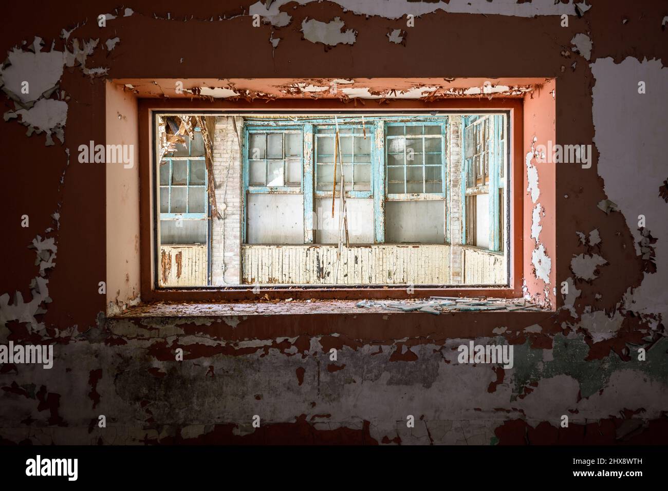 Mirando las ventanas viejas a través de un marco de ventana con pintura descascarada. Foto de stock