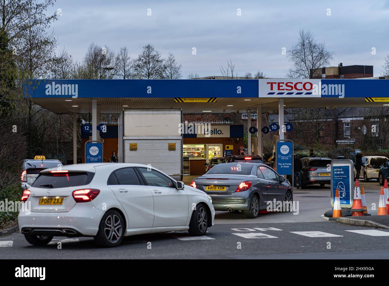 Wigan, Reino Unido: 10 de marzo de 2022: Poner en cola los coches esperando para comprar combustible en una estación de llenado de gasolina Tesco, ya que los conductores británicos pánico comprar combustible Foto de stock