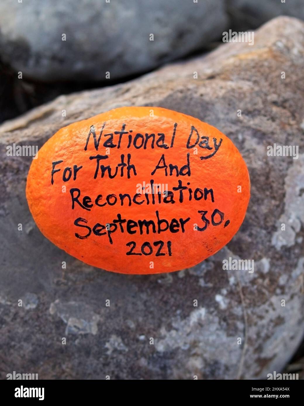 Piedra pintada de naranja con las palabras Día Nacional de la Verdad y la Reconciliación 30 de septiembre de 2021 salió en el Parque Nose Hill como monumento conmemorativo, Calgary, Canadá Foto de stock