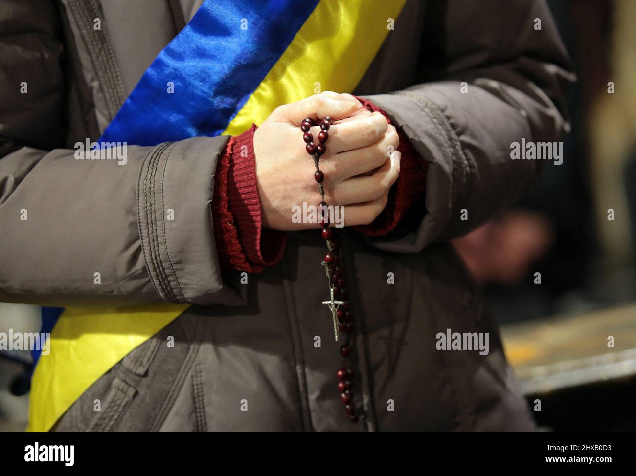 Lviv, Ucrania. 10th Mar, 2022. LVIV, UCRANIA - 10 DE MARZO de 2022 - Una  mujer que lleva una cinta de bandera ucraniana tiene un rosario durante una  oración ecuménica por terminar