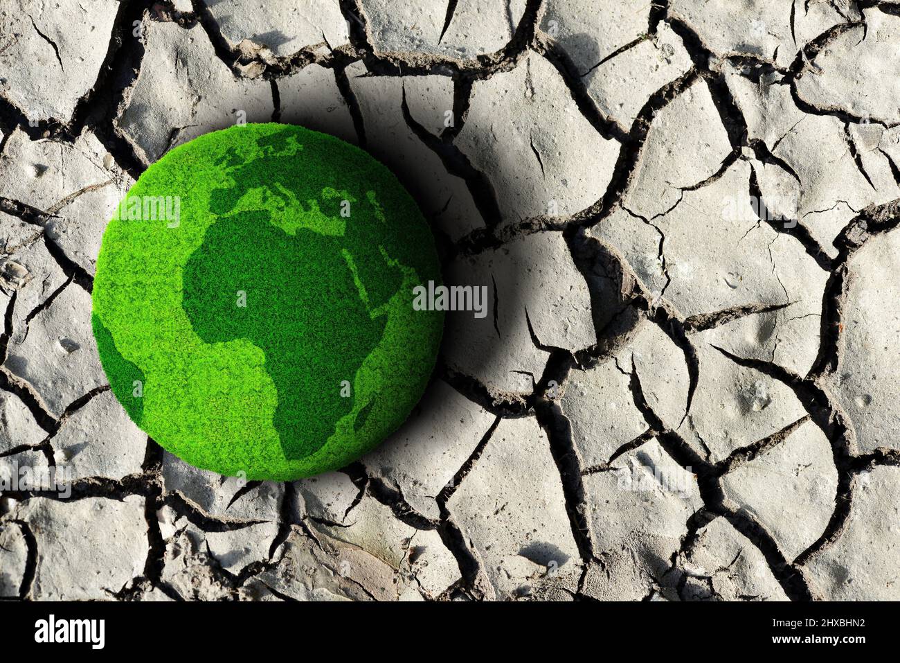 Planeta verde en el suelo seco agrietado. Concepto de cambio climático o calentamiento global. Foto de stock