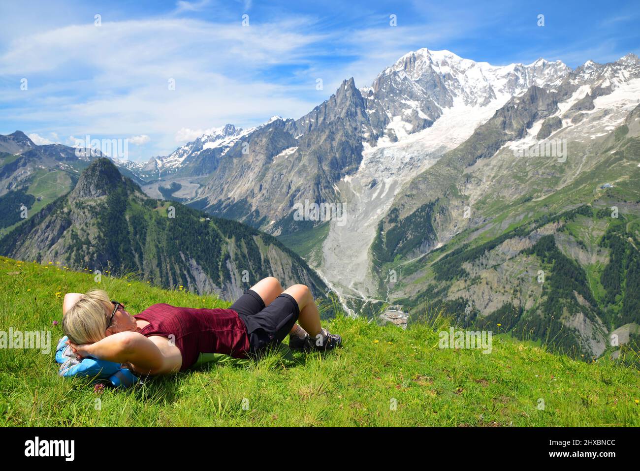 Turista tumbado en un prado en el día soleado, en el fondo Mont Blanc ( Monte Bianco ) cordillera. Valle de Aosta, Italia. Foto de stock