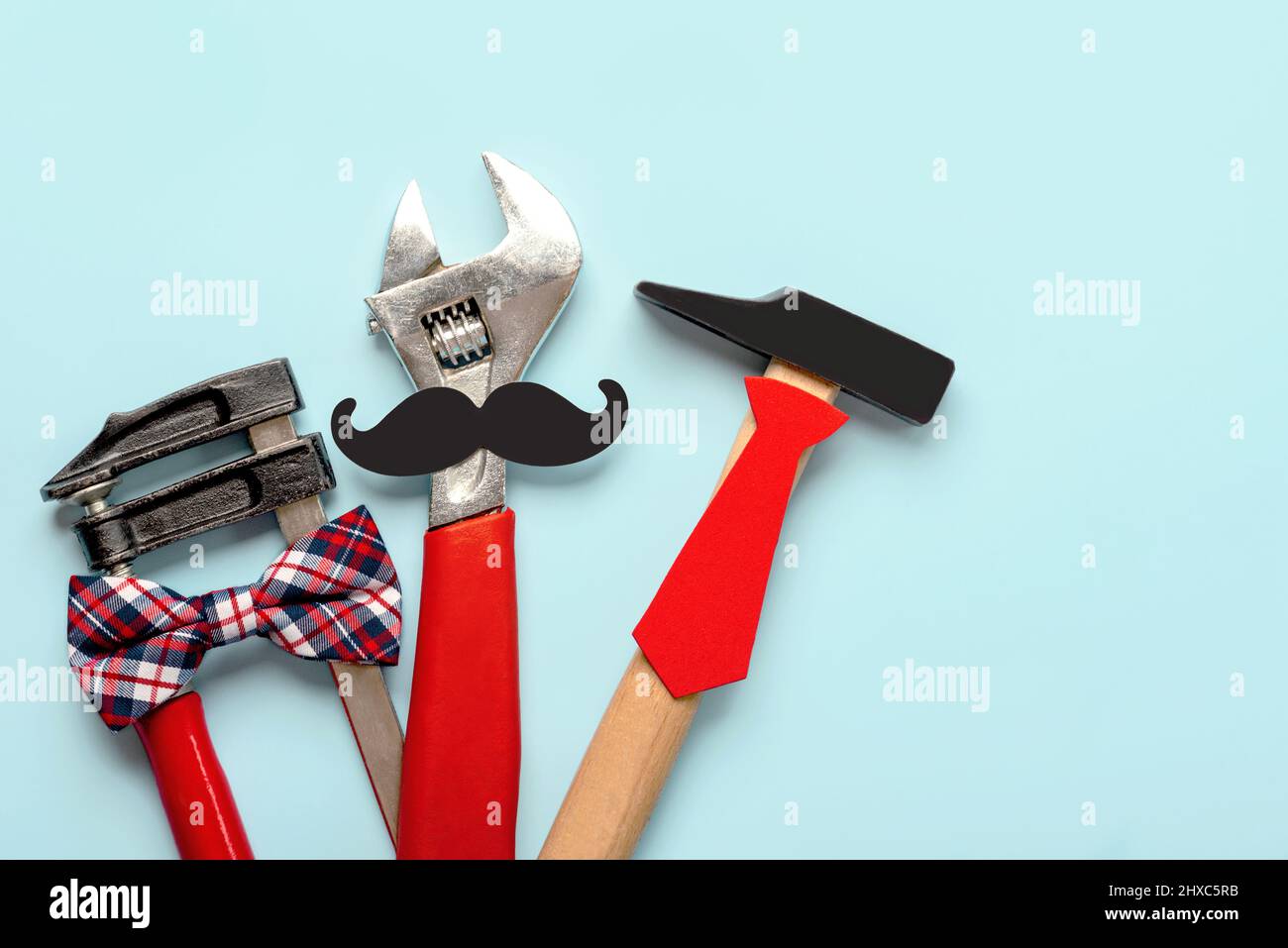 Feliz día del Padre. Vista superior de las herramientas de trabajo con lazo, falso bigote y corbata sobre fondo azul. Concepto de celebración del Día del Padre Foto de stock