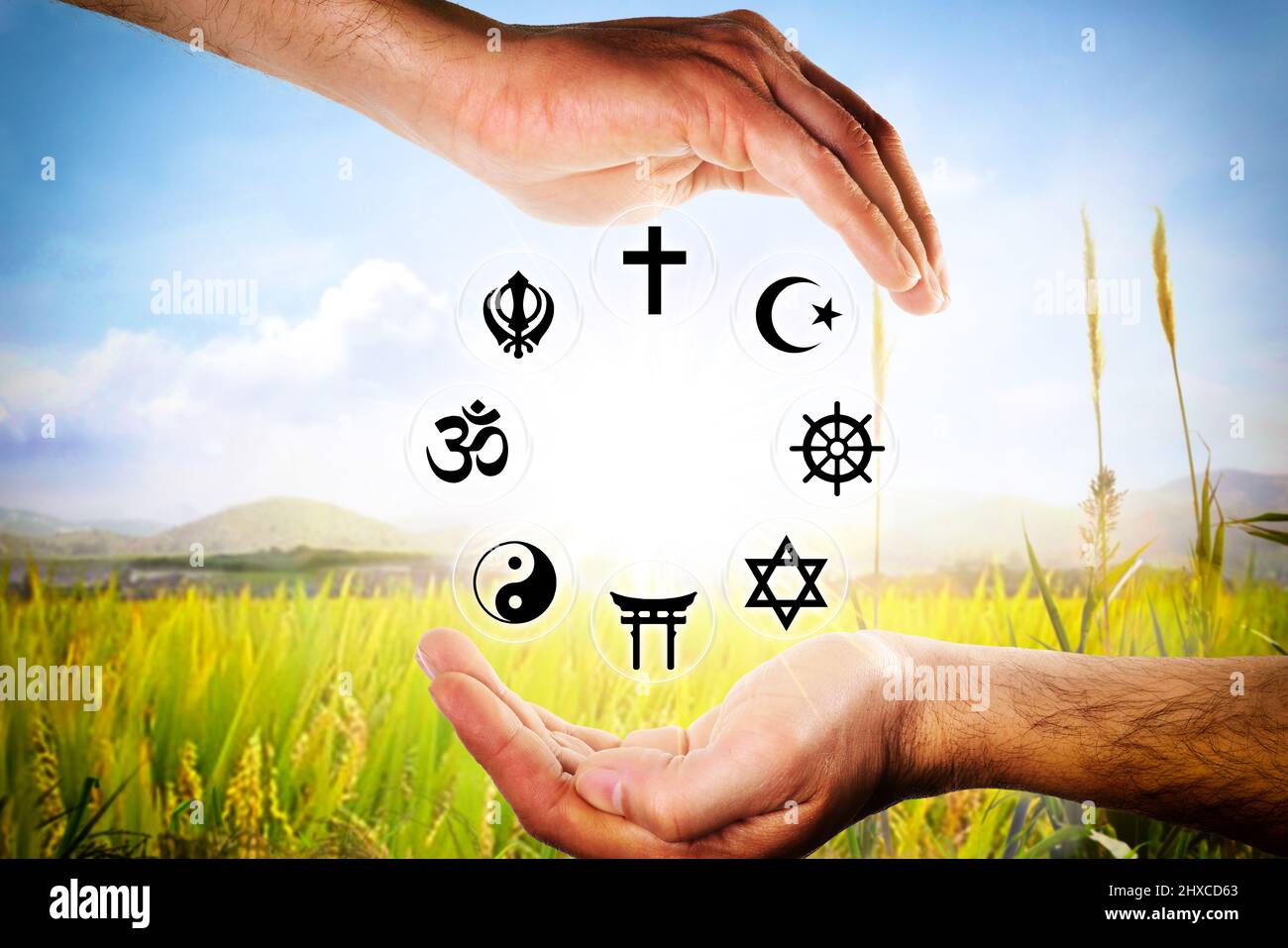 Manos que abarcan símbolos de las religiones más representativas con un fondo natural. Composición horizontal. Foto de stock