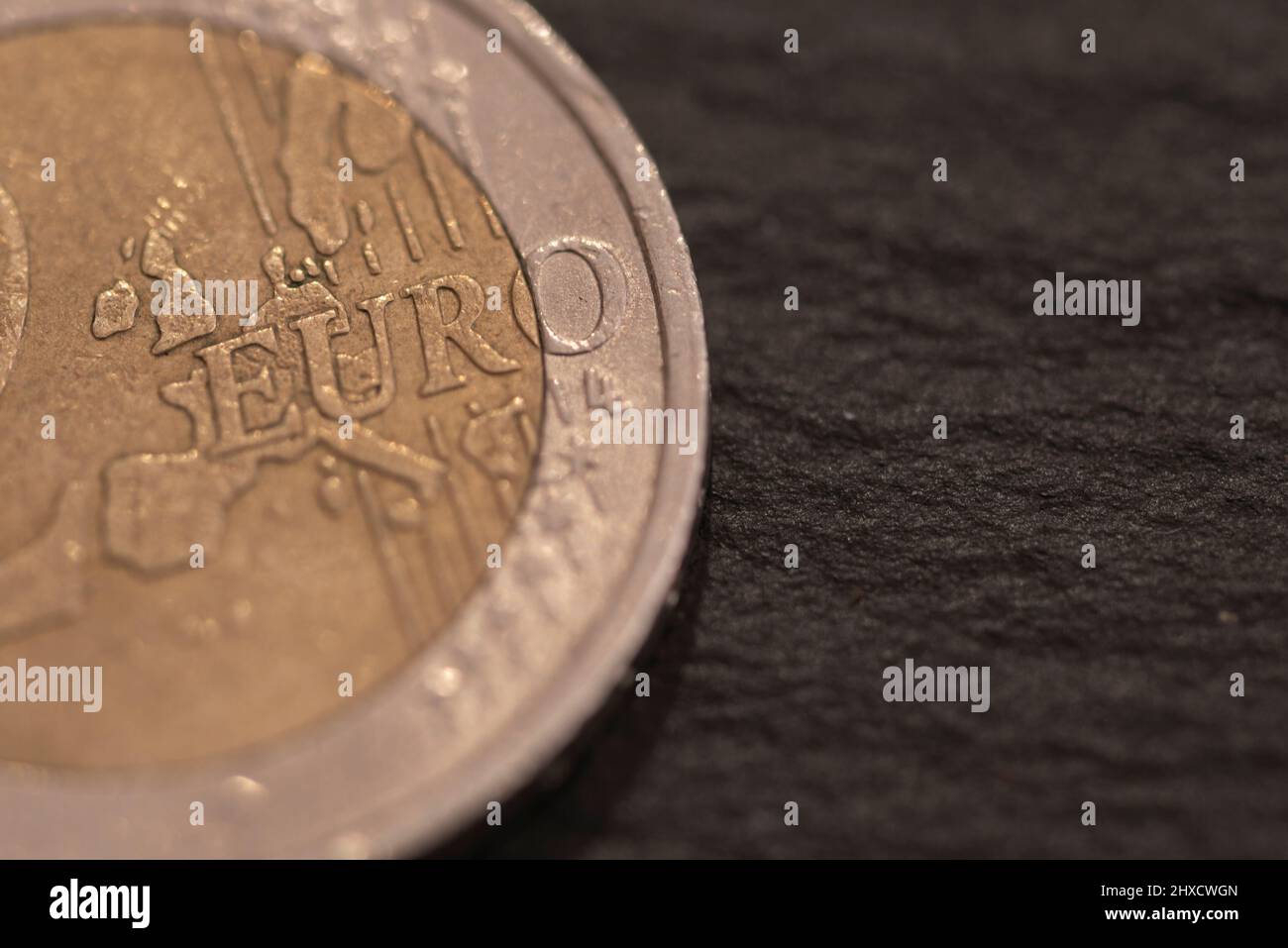 Moneda de dos euros, se encuentra en pizarra negra. Foto de stock