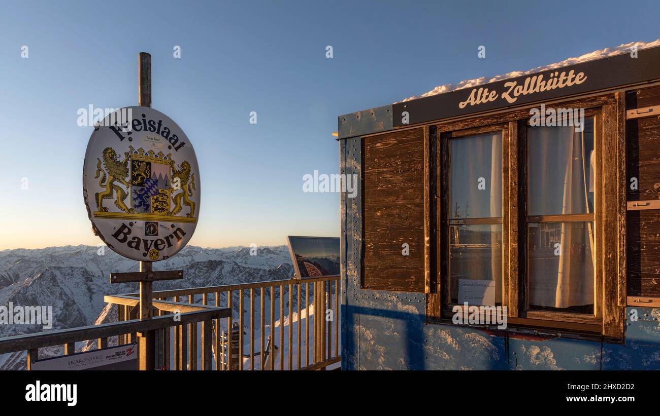 Ánimo matutino en el Zugspitze, amanecer en la montaña más alta de Alemania 'Top of Germany'. Antigua cabaña aduanera y firmar 'Estado Libre de Baviera Foto de stock