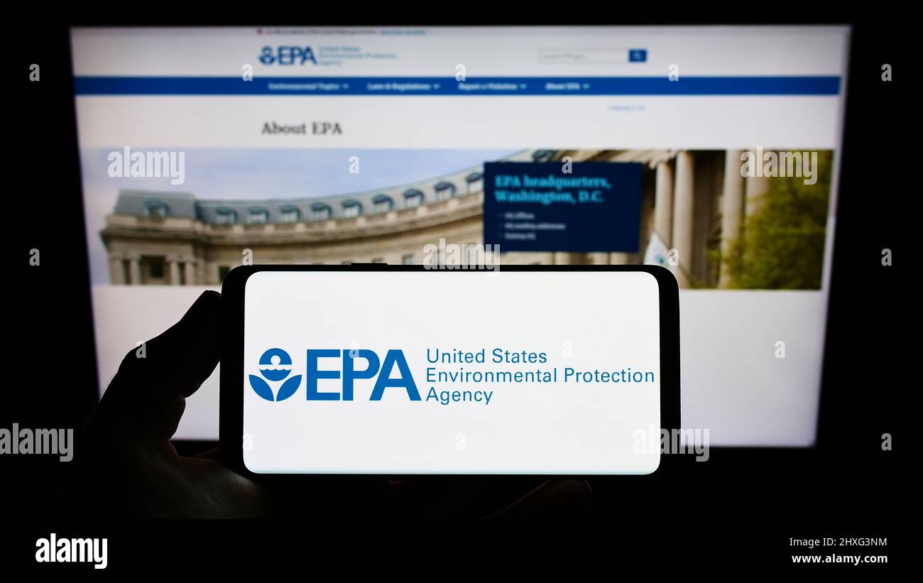 Persona que sostiene el smartphone con el logotipo de la Agencia de Protección Ambiental de EE.UU. (EPA) en la pantalla delante del sitio web. Enfoque en la pantalla del teléfono. Foto de stock