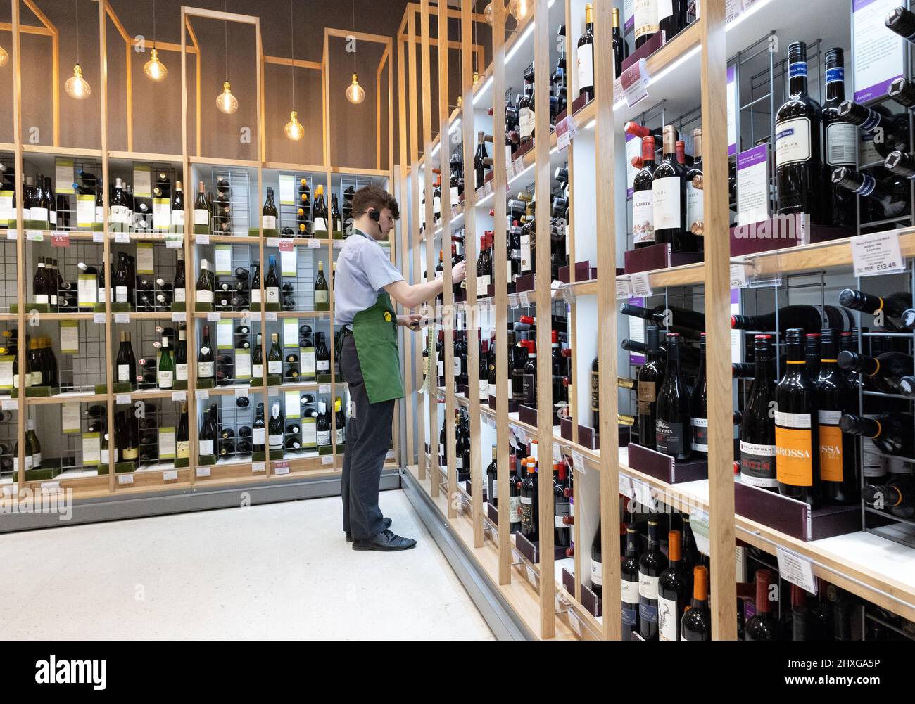 Supermercado del departamento de vino del Reino Unido; un miembro del personal que trabaja en el pasillo del vino, supermercado waitrose del Reino Unido Foto de stock