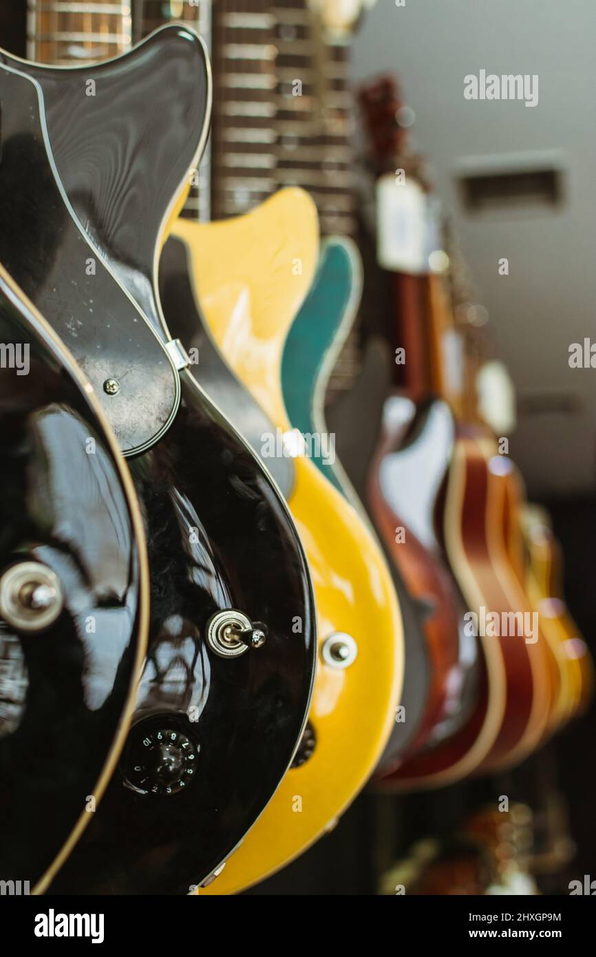 Fila de guitarras eléctricas en una tienda de instrumentos musicales. Partes de guitarra, cuerpo, negro, azul, amarillo, azul Foto de stock