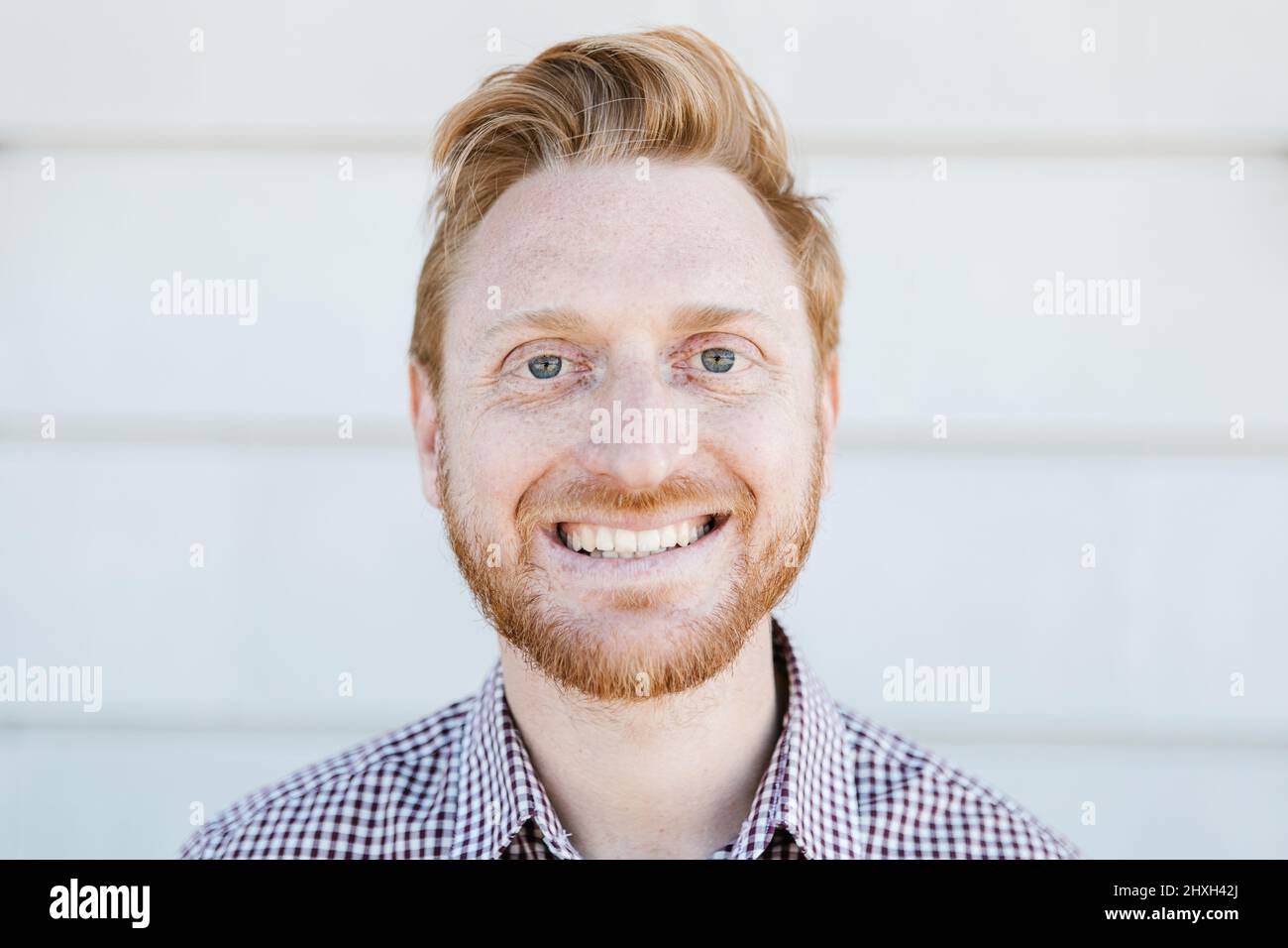 Pelirroja joven hombre adulto sonriendo mientras está de pie al aire libre Foto de stock