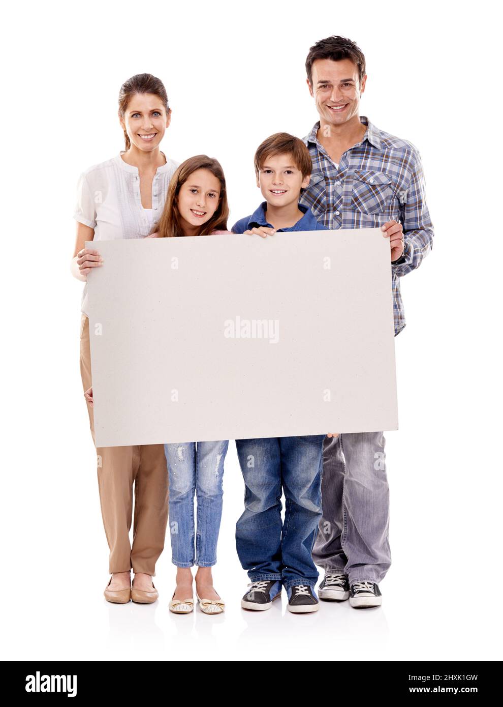 Como. Estudio de una feliz familia de pie con un cartel en blanco para el copyspace. Foto de stock