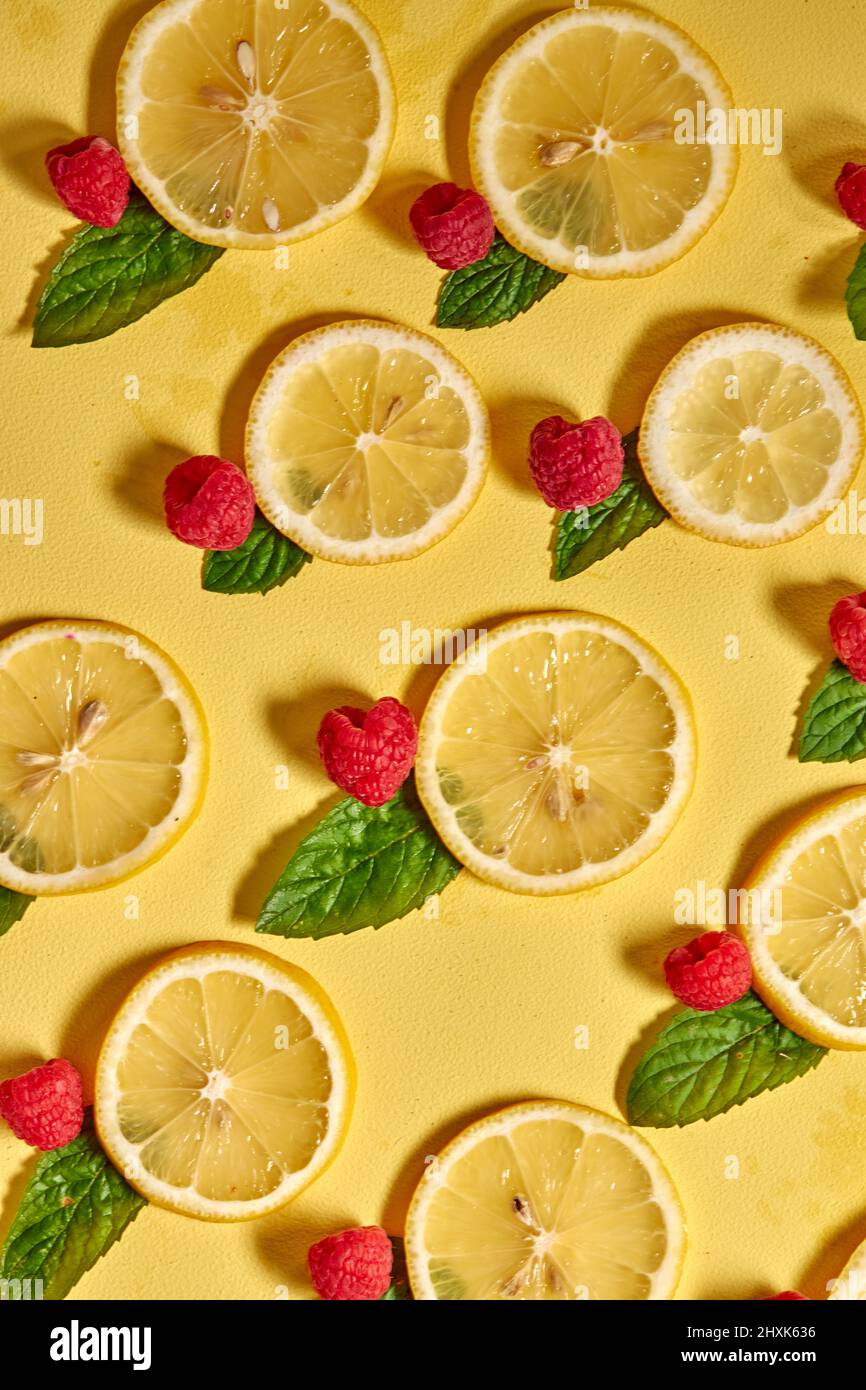 Alta vitamina C. Brillante Limón fresco y fruta de frambuesa con menta aislada sobre fondo amarillo. Vista superior, espacio de copia, primer plano Foto de stock