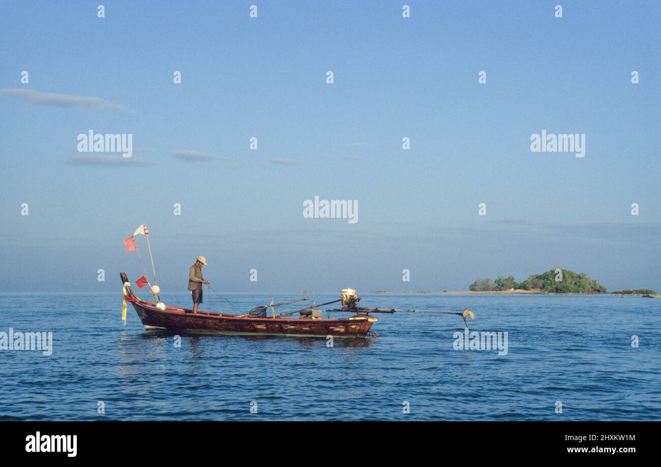 Ein Fischer kontrolliert seine Netze von seinem traditionellen Longtail-Boot aus vor der Küste der Insel Ko Sukorn im Süden Thailands. - Un pescador controla sus redes desde un tradicional barco de cola larga frente a la costa de la isla Ko Sukorn en el sur de Tailandia. Foto de stock