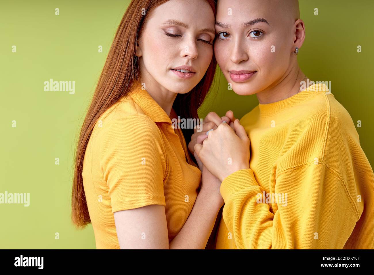 Retrato de dos tiernas y amistosas mujeres europeas de Bald y Redhead manteniendo las manos juntas, posando en Cámara. Espacio de copia. Adorables señoras disfrutan de la vida, amigo Foto de stock