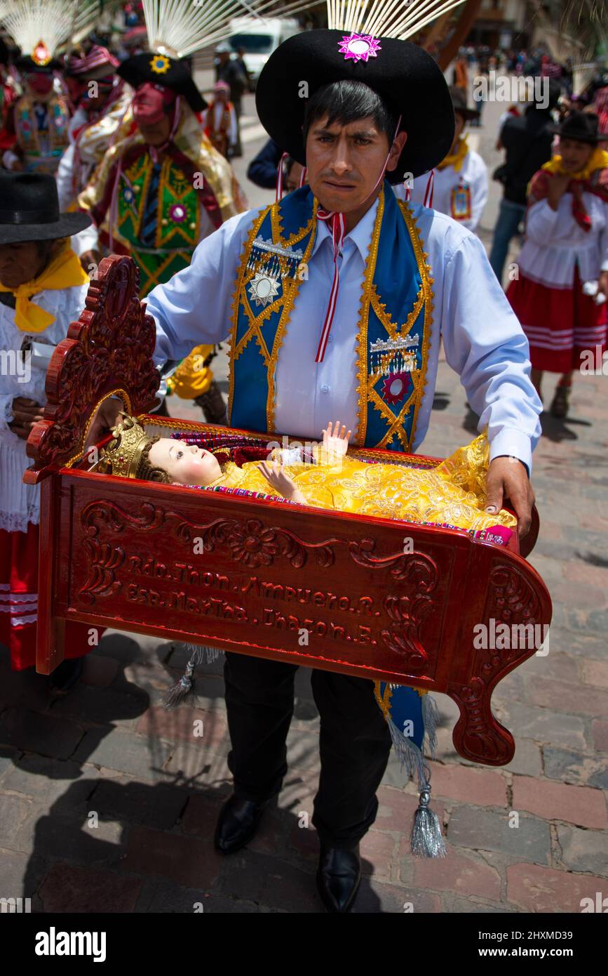 Cuzco, Perú - 25 de diciembre de 2013: Un hombre sosteniendo una cuna con un bebé Jesús y llevando ropa tradicional durante la Huaylia el día de Navidad en el Pla Foto de stock