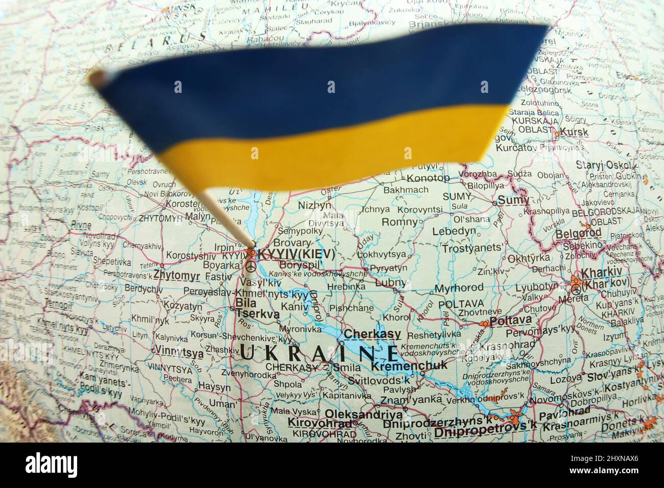Vista de pájaro de cerca de la bandera amarilla azul ucraniana pegada en un mapa que muestra la capital Kyiv y la palabra Ucrania. Muestra la ubicación y las ciudades Foto de stock