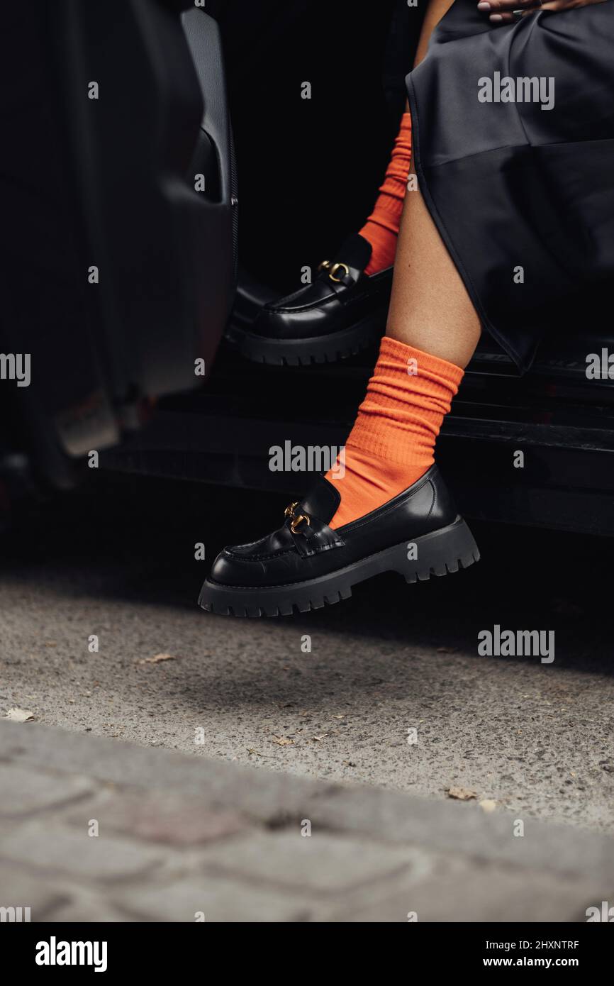 Mujer con estilo irreconocible con zapatos de moda y calcetines naranjas para salir del coche Foto de stock