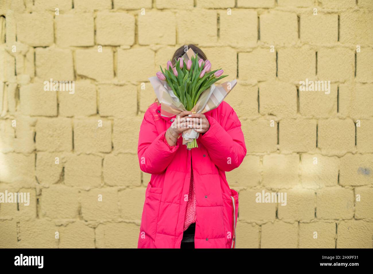 Retrato de mujer, sosteniendo flores de tulipán de ramo violeta. Ocultando cara. Regalo sorpresa obsequio de primavera. Celebración, vacaciones Foto de stock