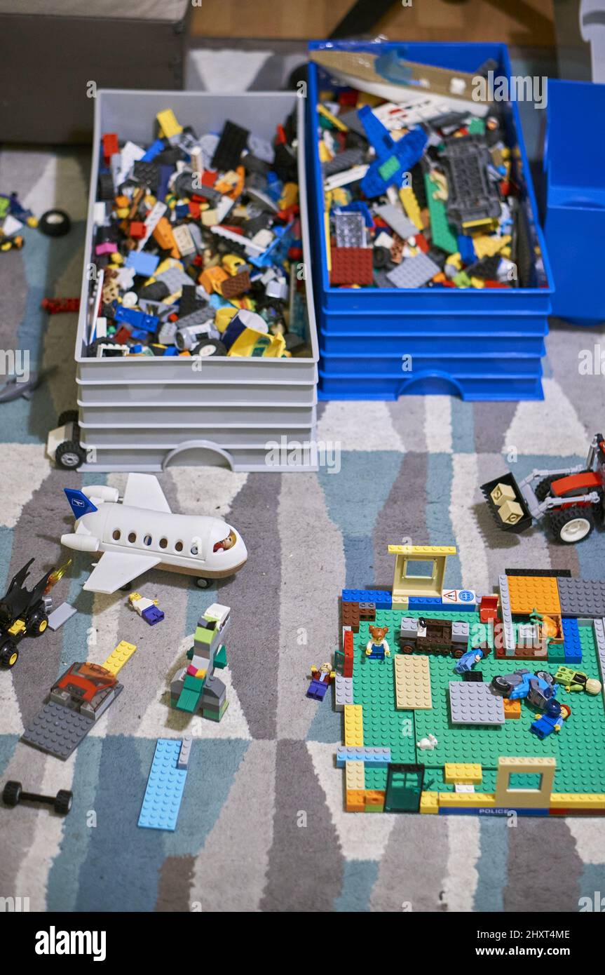 Contenedores completos junto a juegos de ladrillos de marca Lego con  figurillas en una alfombra en un cuarto de juegos Fotografía de stock -  Alamy