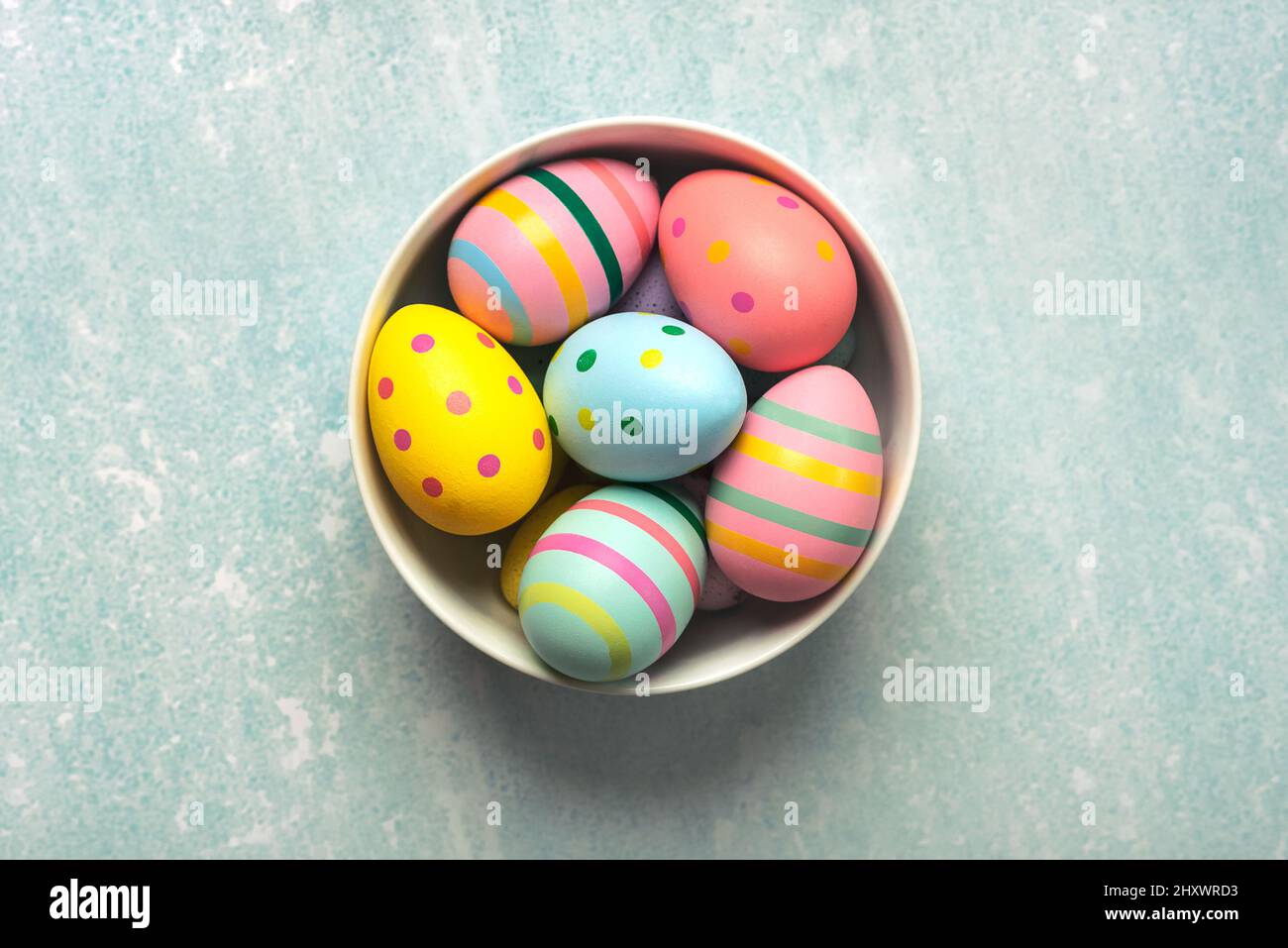 Felices Pascuas. huevos de pascua coloreados pintados en un tazón en la mesa azul Foto de stock