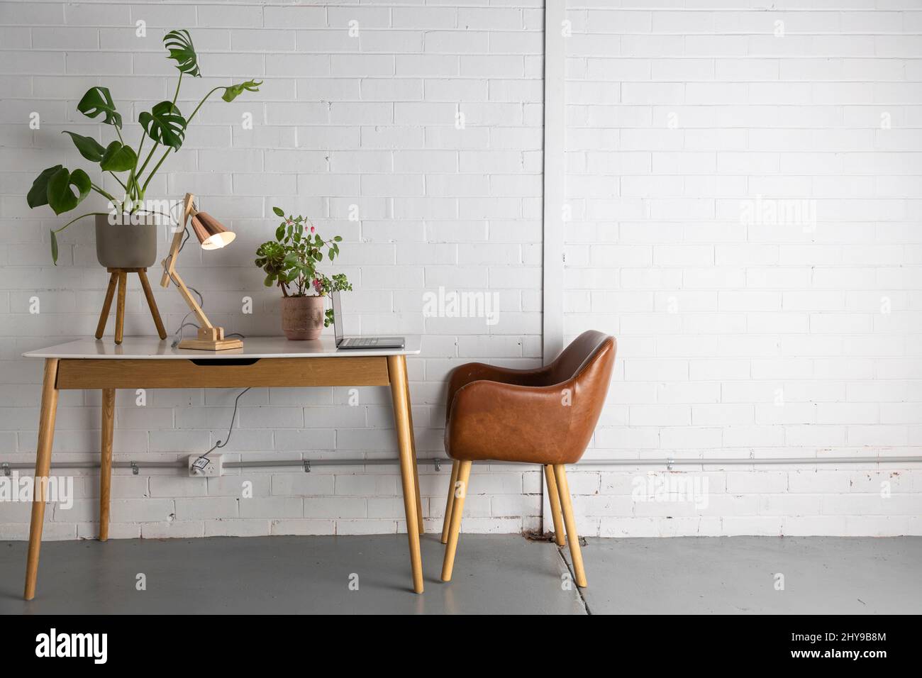 Un espacio de trabajo de oficina en casa en una casa con suelo de hormigón y paredes de ladrillo. Estilo escandinavo. Foto de stock