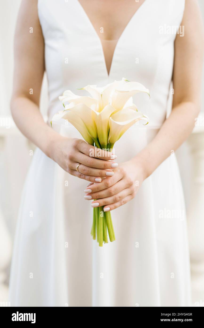 Ramo de novia blanco de lirios calla en las manos de la novia Foto de stock