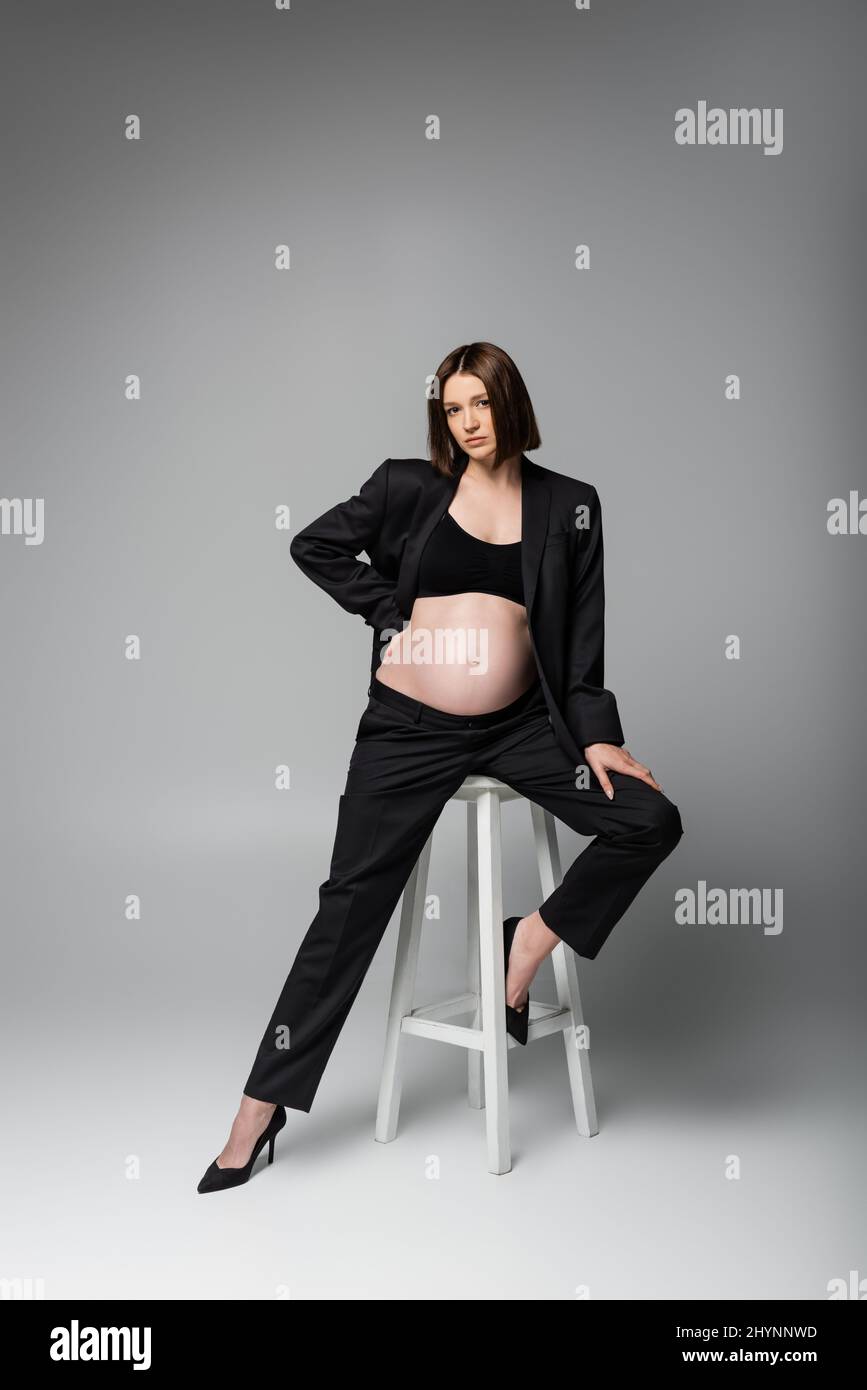 es suficiente pierna dramático Mujer embarazada en traje sentada en silla sobre fondo gris Fotografía de  stock - Alamy