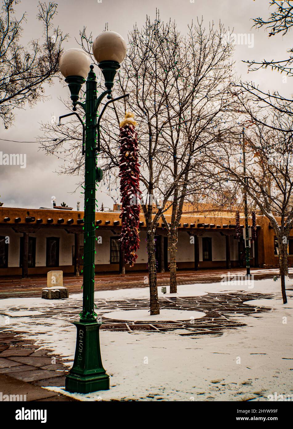 Largas ristras de pimiento rojo atadas con nieve en una mañana de invierno en la histórica plaza de Santa Fe, Nuevo México Foto de stock