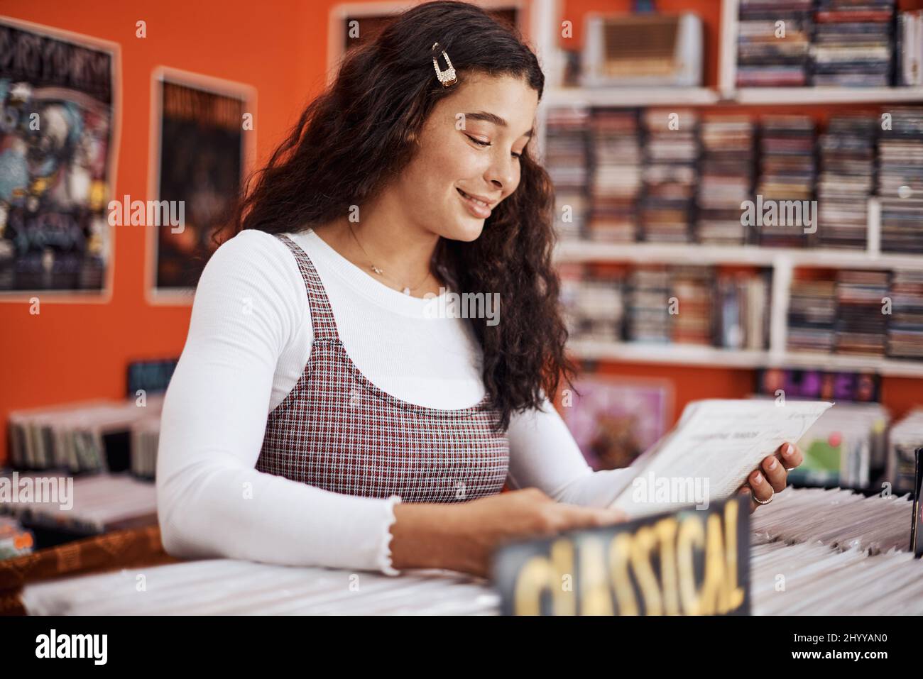 Este es un buen álbum. Foto recortada de una atractiva niña adolescente de pie sola y de compras de discos de música de vinilo en la ciudad. Foto de stock