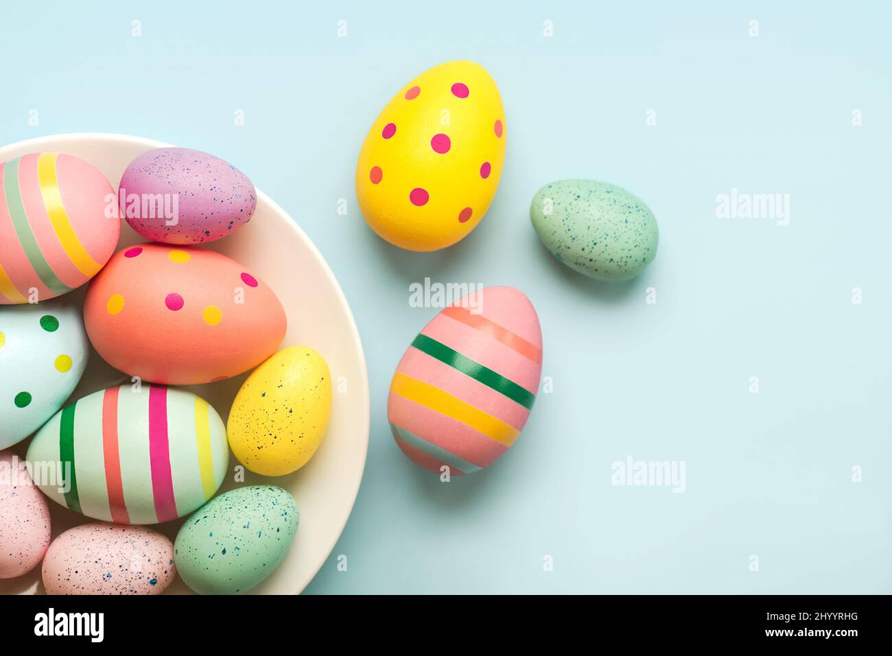 Felices Pascuas. huevos de pascua coloreados pintados en un tazón en la mesa azul Foto de stock