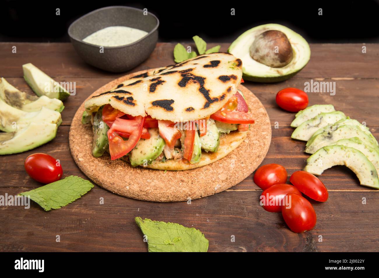 Arepas - Comida Colombiana Tradicional Originalmente de América Latina dispuesta sobre una vieja mesa rústica de madera mezclada con carne, verdura y aguacate Foto de stock