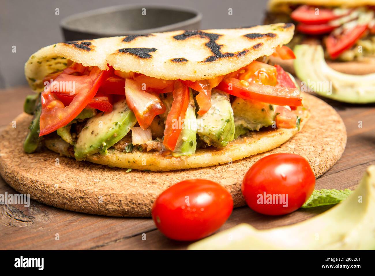 Arepas - Comida Colombiana Tradicional Originalmente de América Latina dispuesta sobre una vieja mesa rústica de madera mezclada con carne, verdura y aguacate Foto de stock