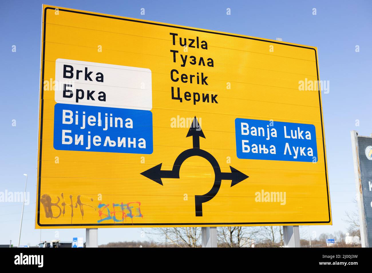 Señal de carretera amarilla en el distrito de Brcko en alfabeto latino y cirílico que muestra los destinos Foto de stock