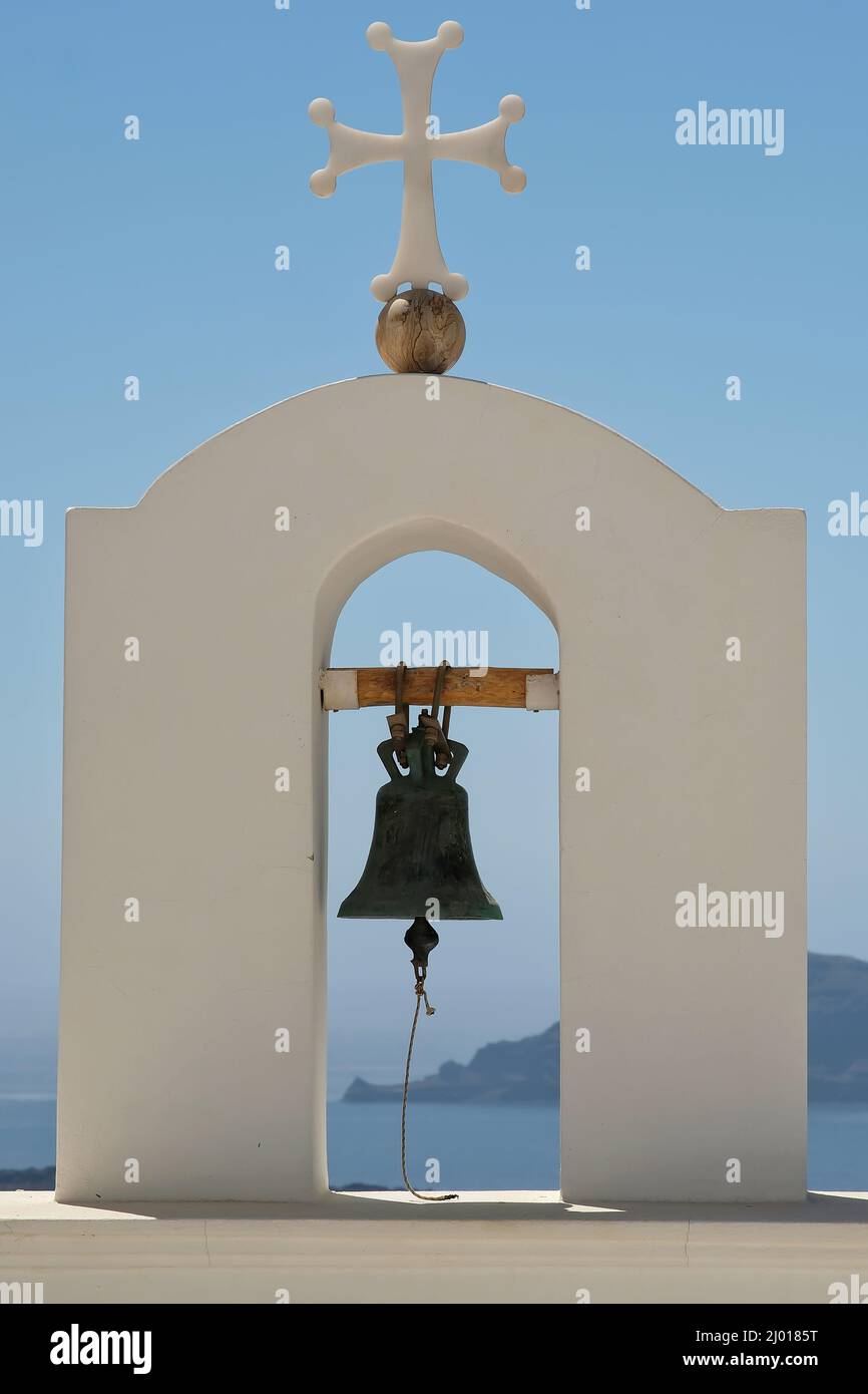 Una campana de la iglesia y una cruz en la cima de una iglesia ortodoxa griega y un hermoso cielo azul en Santorini Foto de stock