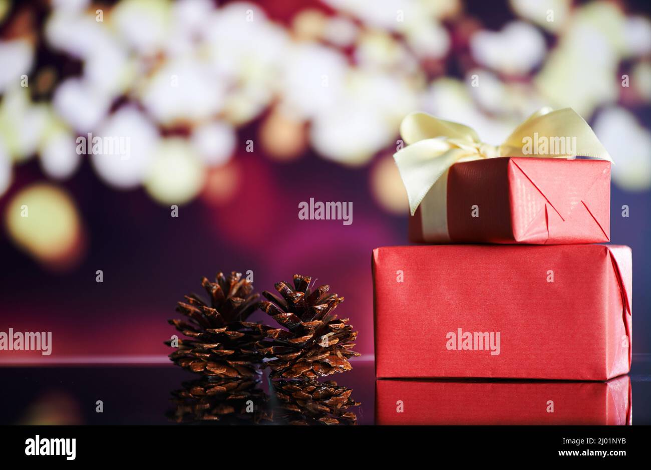 La Navidad está aquí. Foto de regalos de Navidad y conos de pino sobre una mesa con luces de Navidad en el fondo. Foto de stock