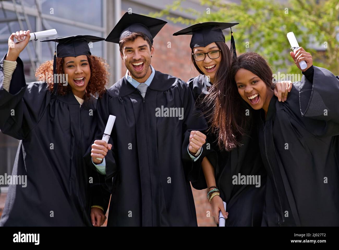 Éxito de la educación extática. Fotografía de estudiantes universitarios emocionados en el día de graduación. Foto de stock