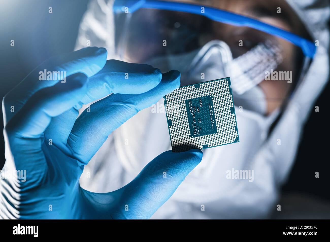 Ingeniero en mono estéril sostiene Microchip con guantes en una fábrica