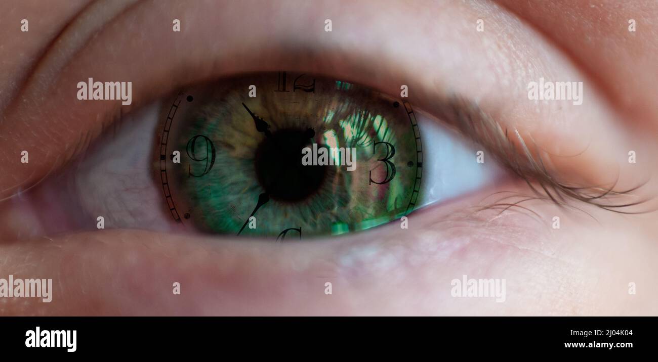 Cara del reloj en el ojo humano , concepto de envejecimiento o paso del tiempo . Primer plano de un ojo verde con concepto de tiempo Foto de stock