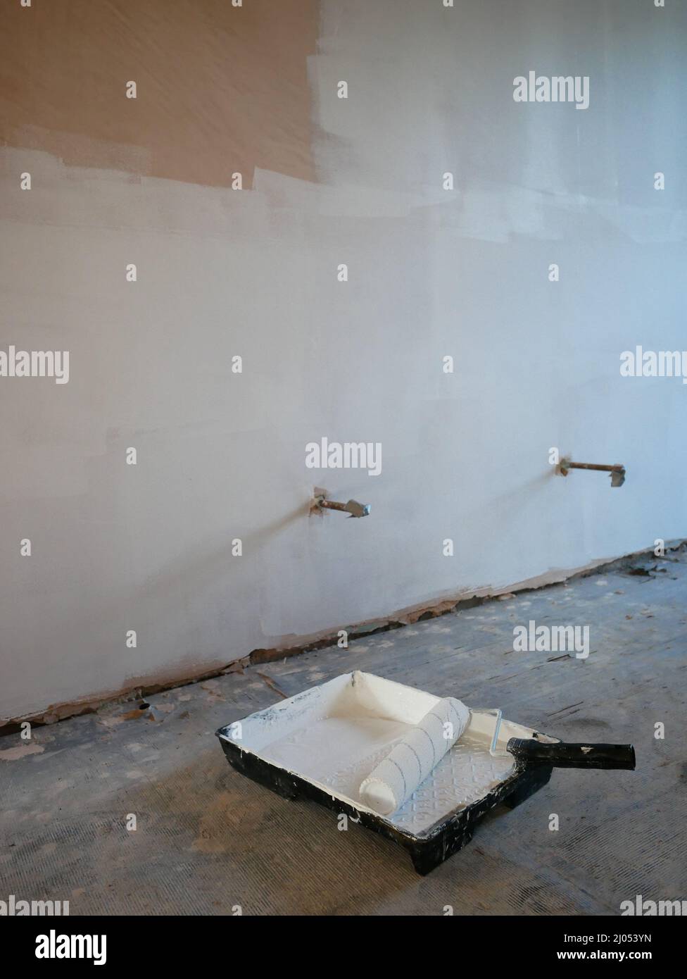 Pintura de capa de niebla sobre nuevas paredes de yeso desnudo en una renovación de la propiedad. Foto de stock